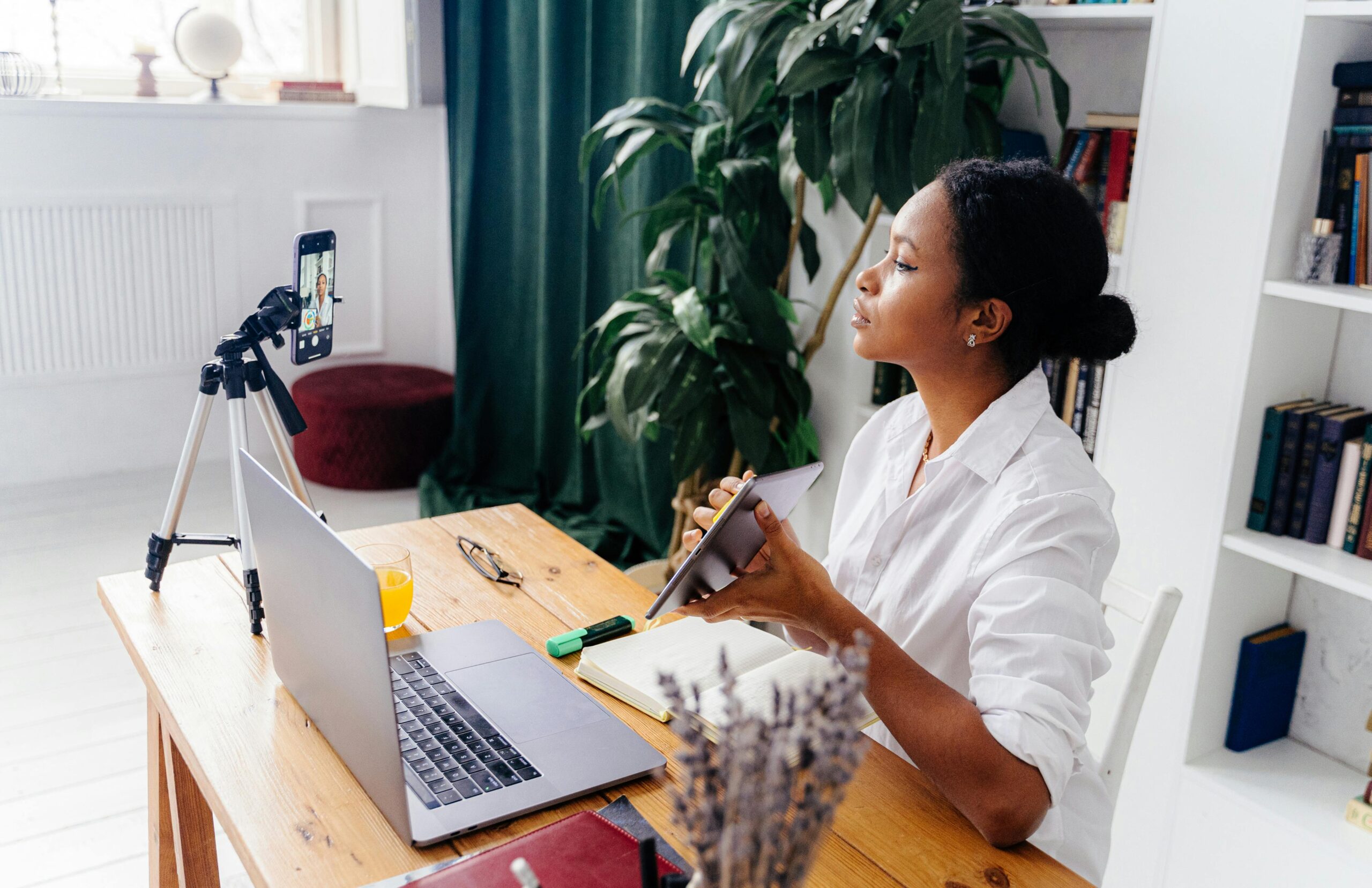 Black woman using electronic devices for vlogging indoors at home office.